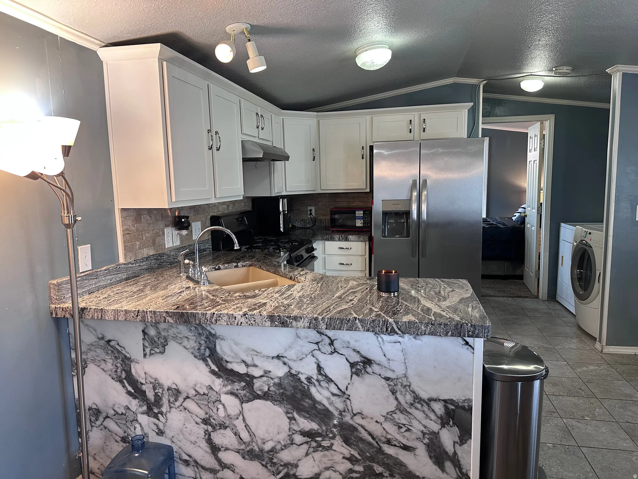 Kitchen featuring white cabinetry, stone-look countertops, and a full suite of stainless steel appliances