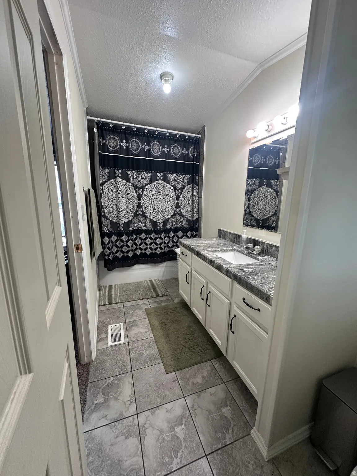 Bathroom featuring a single vanity with a laminate countertop, integrated sink, and white cabinetry