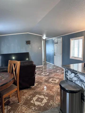 Living area featuring decorative patterned tile flooring, light blue wall paint, and white baseboards