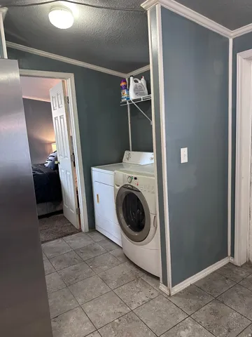 Dedicated utility area featuring tile flooring, a built-in wire shelf, and crown molding accents