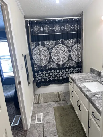 Bathroom featuring a single-sink vanity with white cabinetry, dark hardware, and a stone-finish countertop