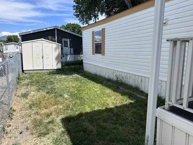 Exterior features include white horizontal siding, brown trim, and a white shed