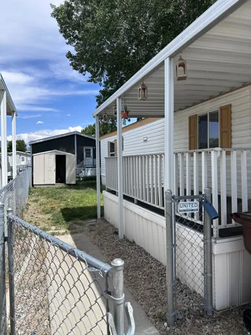 Property exterior featuring white horizontal siding, a covered porch with white railings, and an attached storage shed