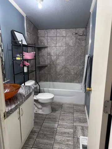 Bathroom featuring a porcelain bathtub, tiled shower surround with built-in corner shelves, and a coordinating tiled floor