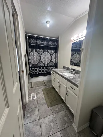 Bathroom featuring a single vanity with a laminate countertop, integrated sink, and white cabinetry