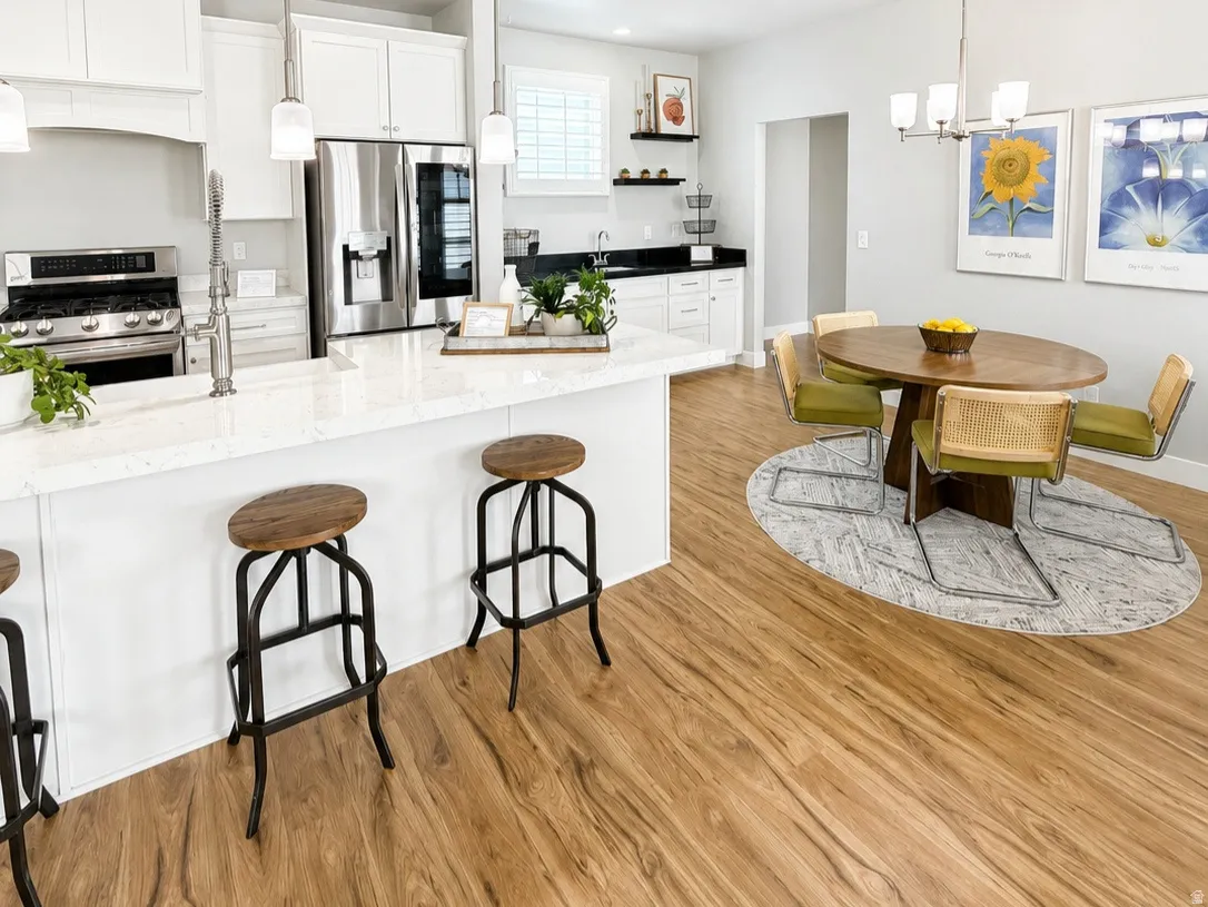Kitchen featuring white cabinetry, stainless steel appliances, a white island with a countertop, and wood-finish flooring throughout