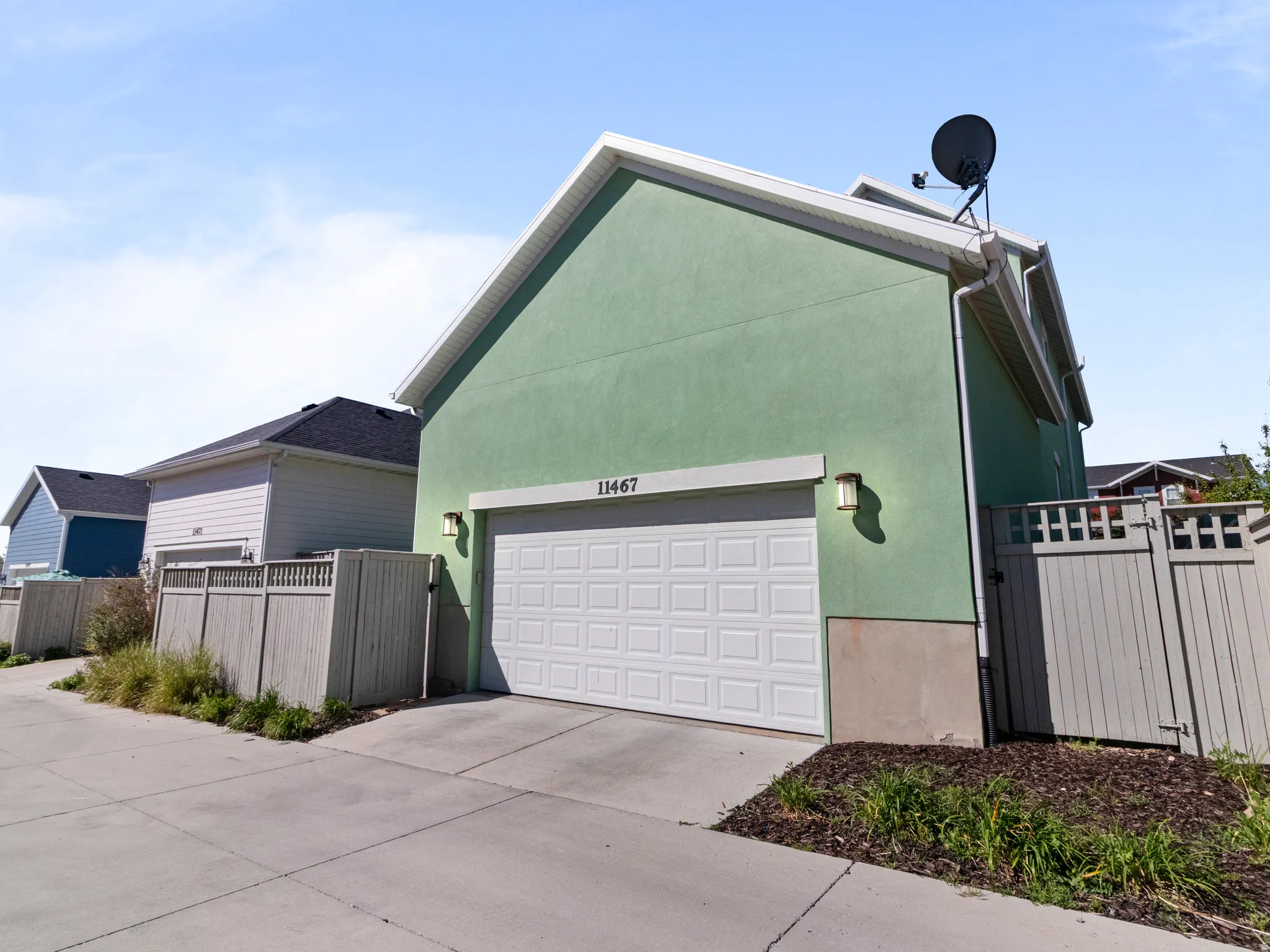 Two-car garage with a white panel door, accented by exterior sconce lighting