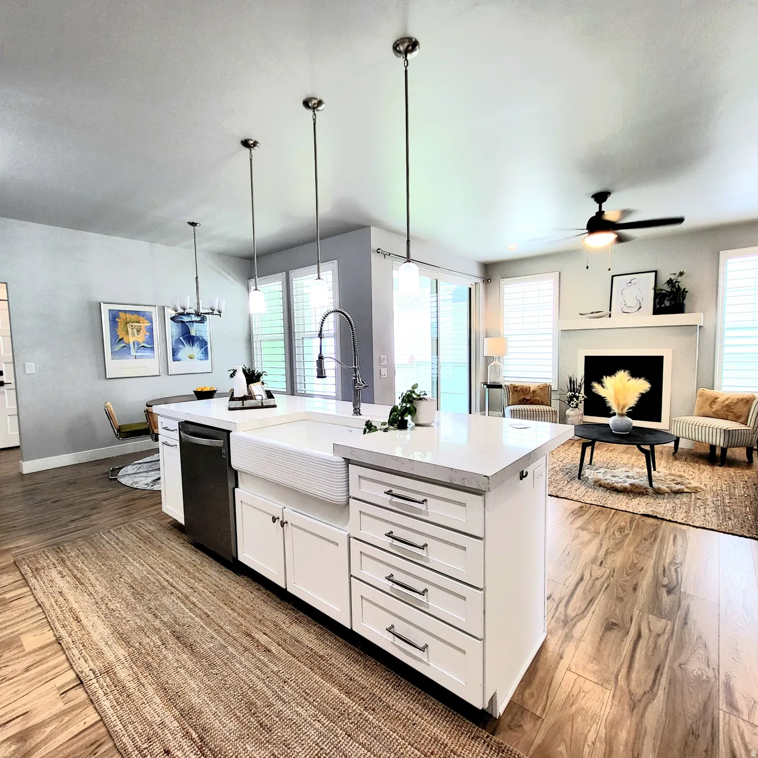 Kitchen island featuring a farmhouse sink, quartz countertop, and white cabinetry with dark pulls