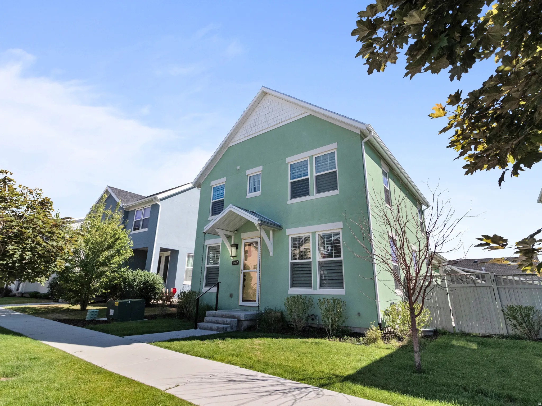Two-story residence featuring light green stucco siding with white trim accents and Jellyfish lights