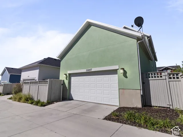 Two-car garage with a white panel door, accented by exterior sconce lighting