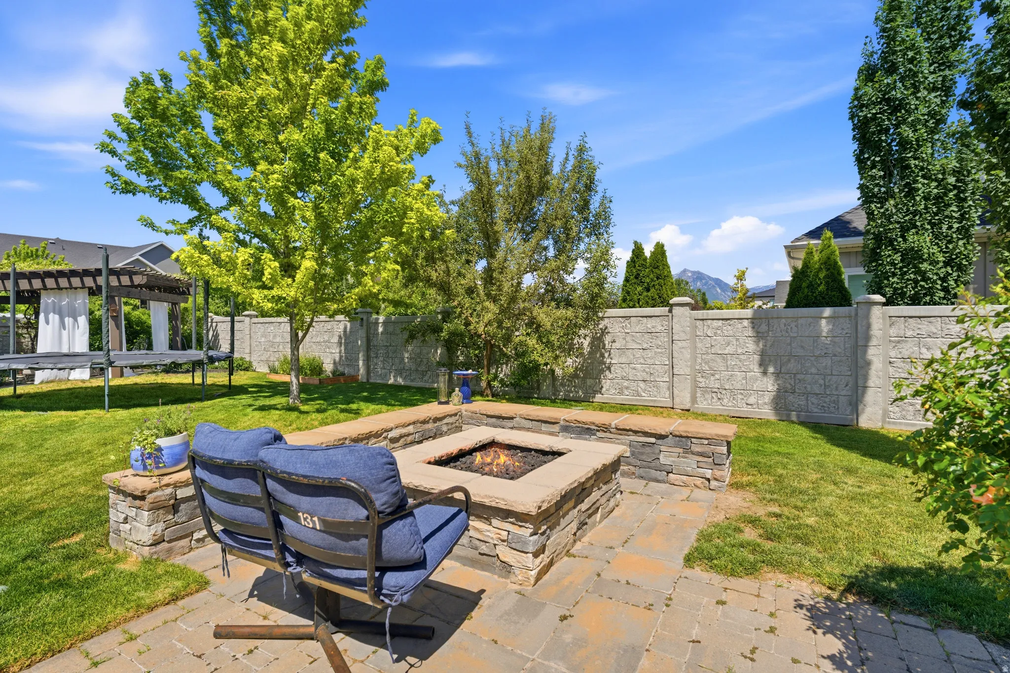 Fully fenced backyard with pergola, gas fire pit, and trampoline
