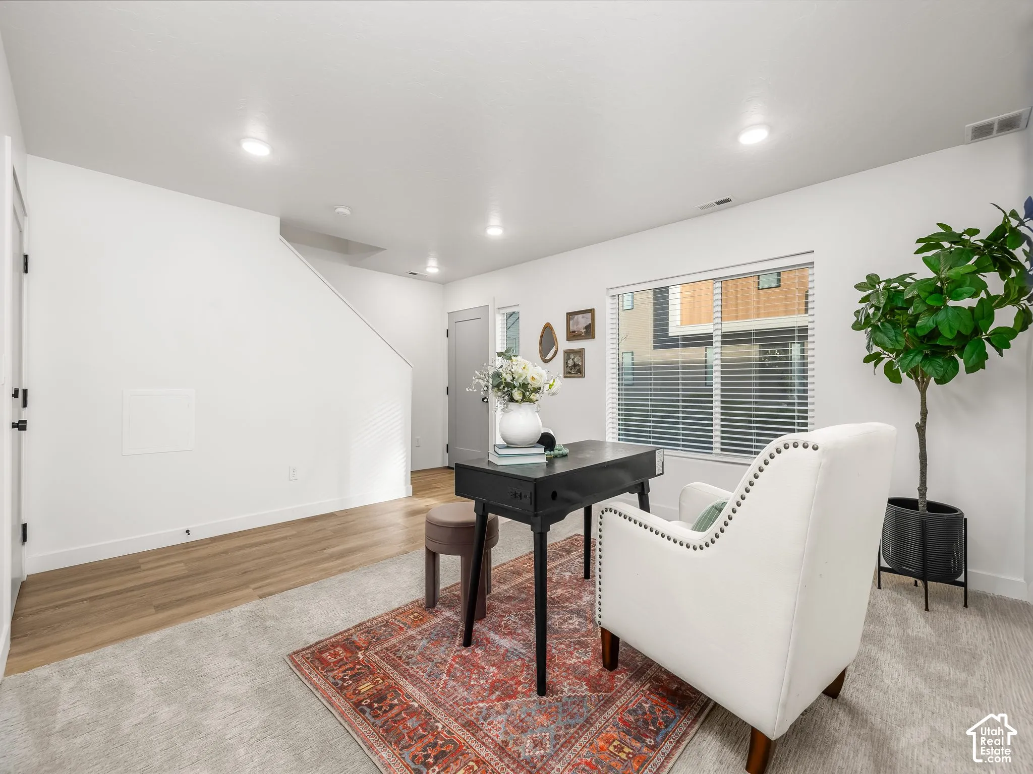 Bright interior space featuring a window with blinds, recessed lighting, wood-finish flooring, and light-toned carpeting