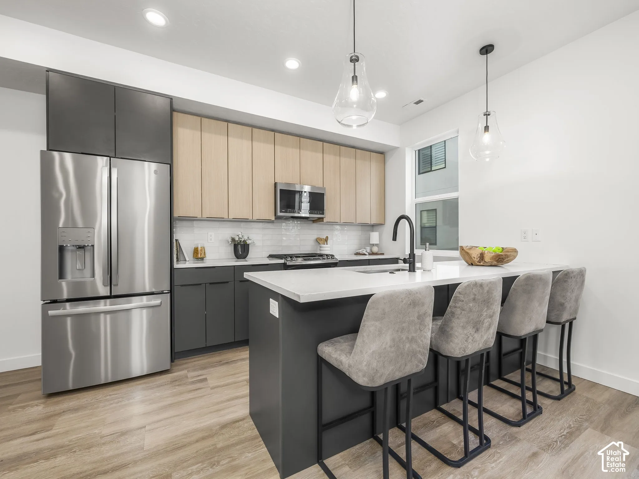 Modern kitchen featuring stainless steel appliances, a white subway tile backsplash, and a large island with seating