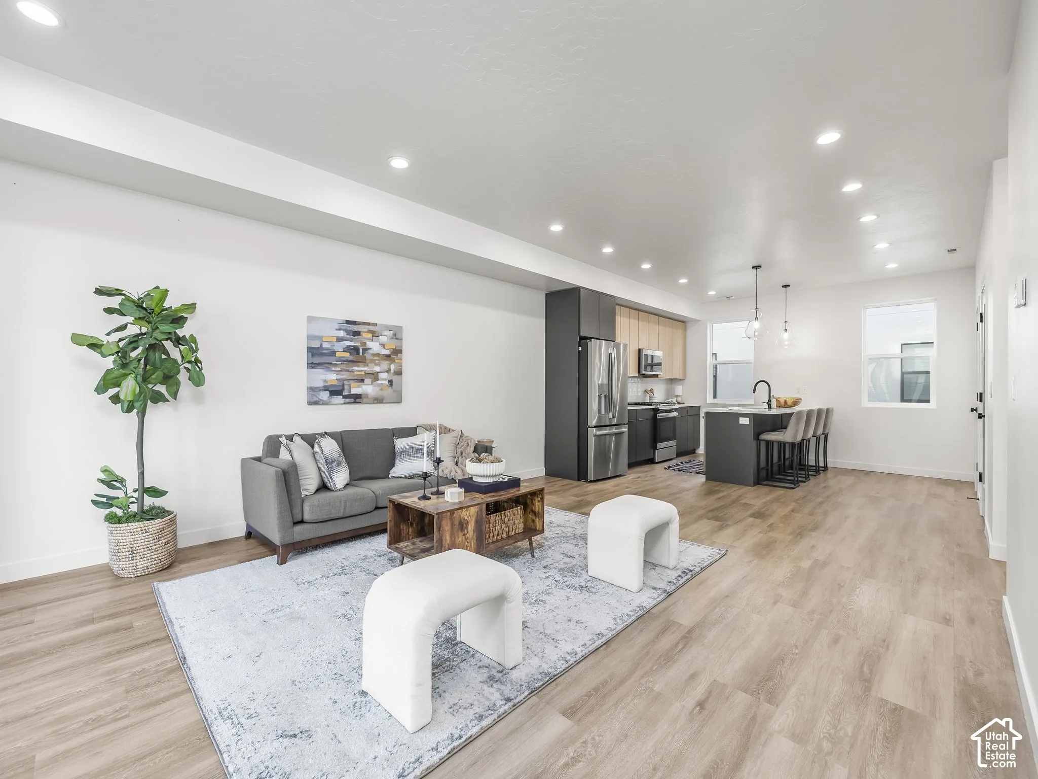 Open-concept living space featuring wood-finish flooring, recessed lighting, and a kitchen with stainless steel appliances