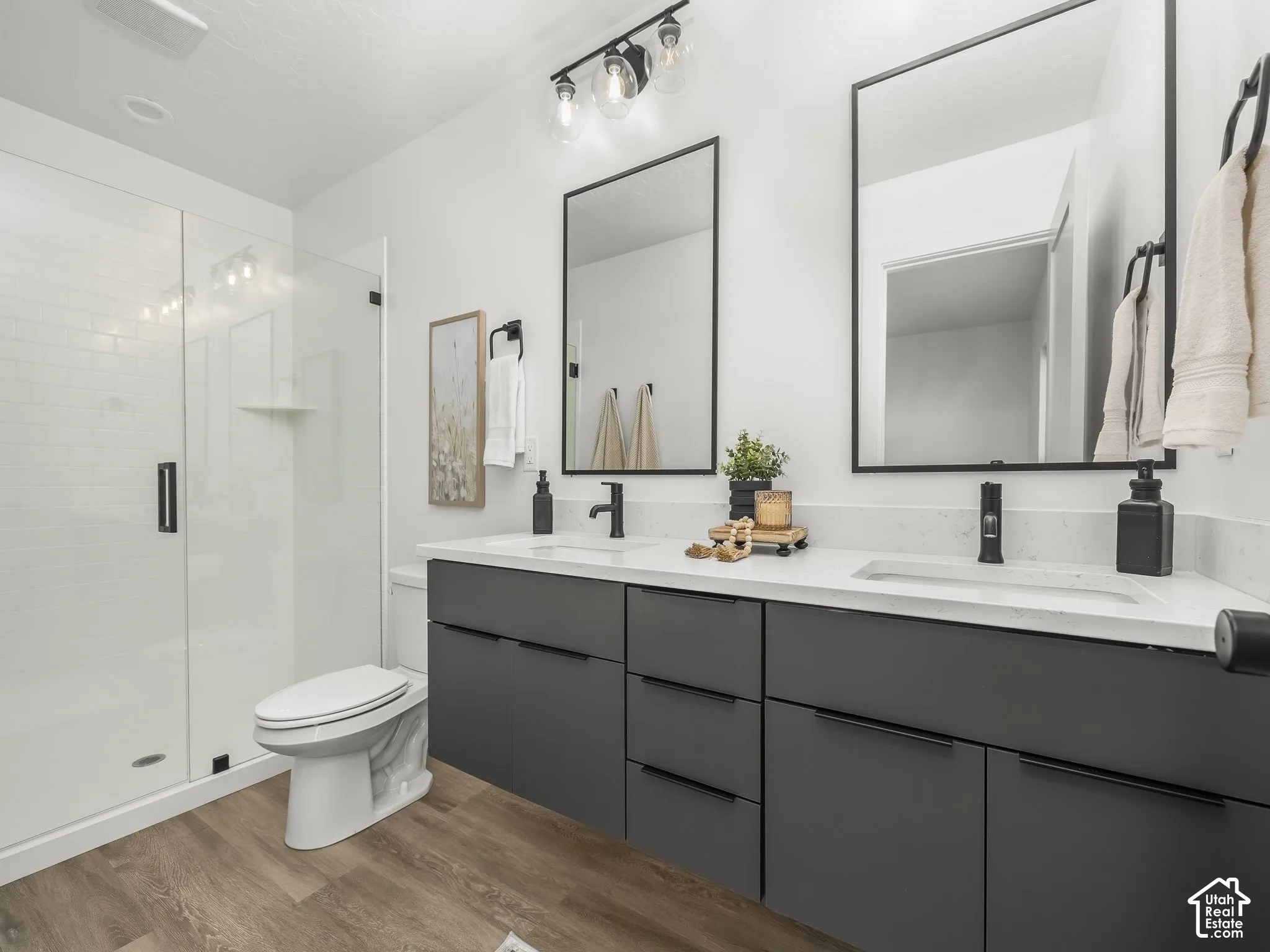 Contemporary bathroom featuring a double vanity with dark cabinetry and white countertops