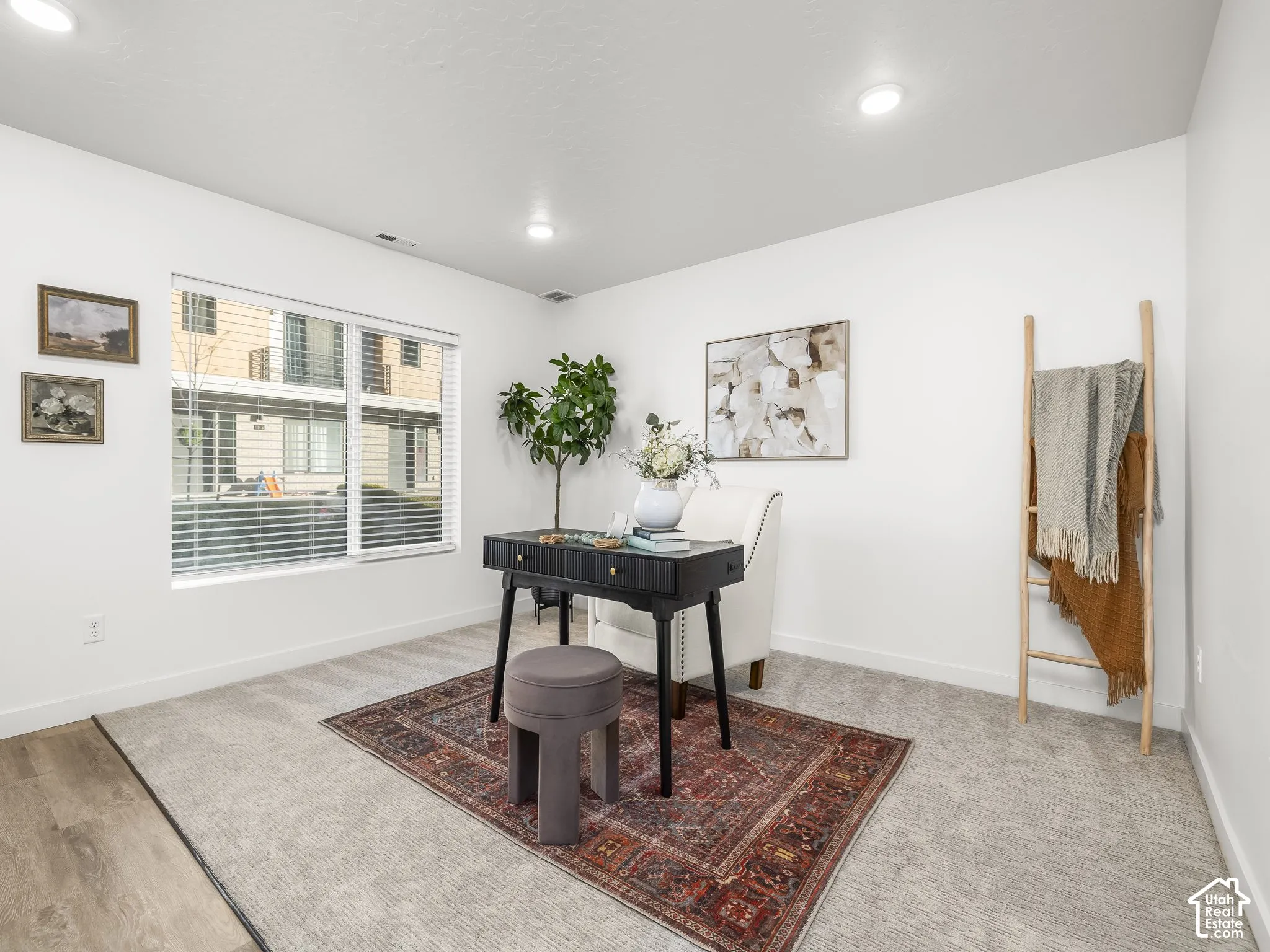 Interior room featuring a large window with horizontal blinds, recessed lighting, and a combination of carpet and wood-finish flooring