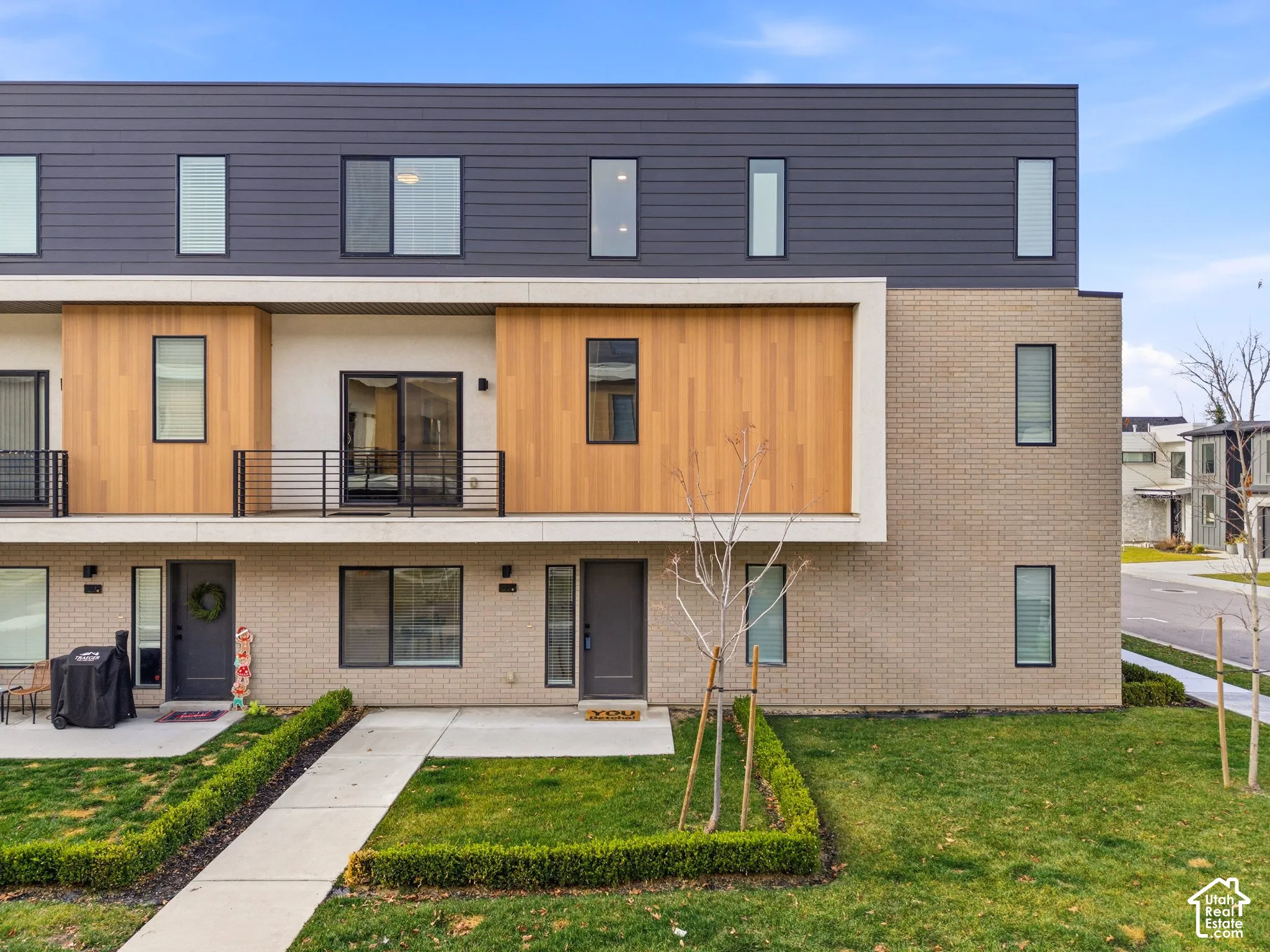 Multi-level townhouse facade featuring a combination of brick, horizontal siding, and wood-panel accents