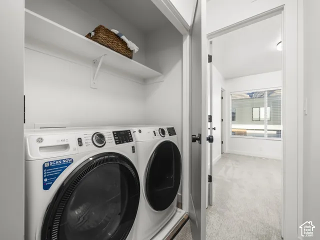 Dedicated laundry area featuring a white front-load washer and dryer set, an overhead storage shelf, and light wall finishes