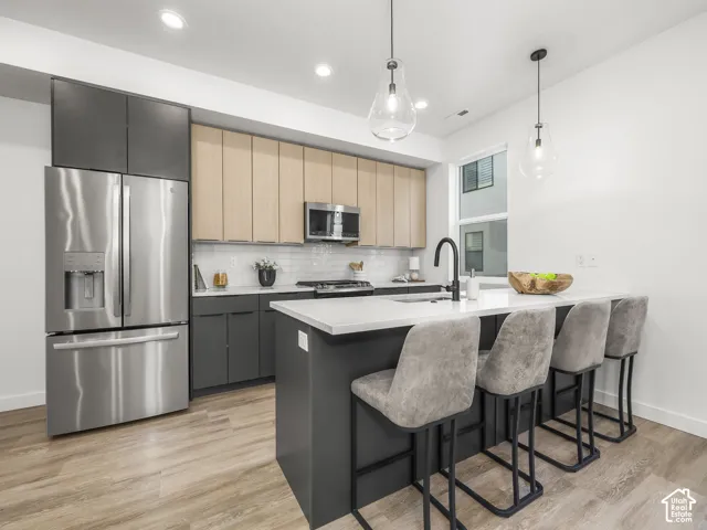 Modern kitchen featuring stainless steel appliances, a white subway tile backsplash, and a large island with seating