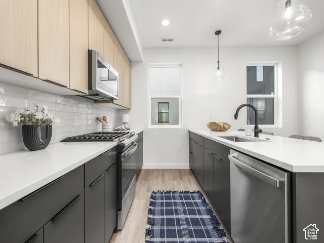 Modern kitchen featuring two-tone cabinetry with light wood-finish upper cabinets and dark lower cabinets, white countertops, and a subway tile backsplash