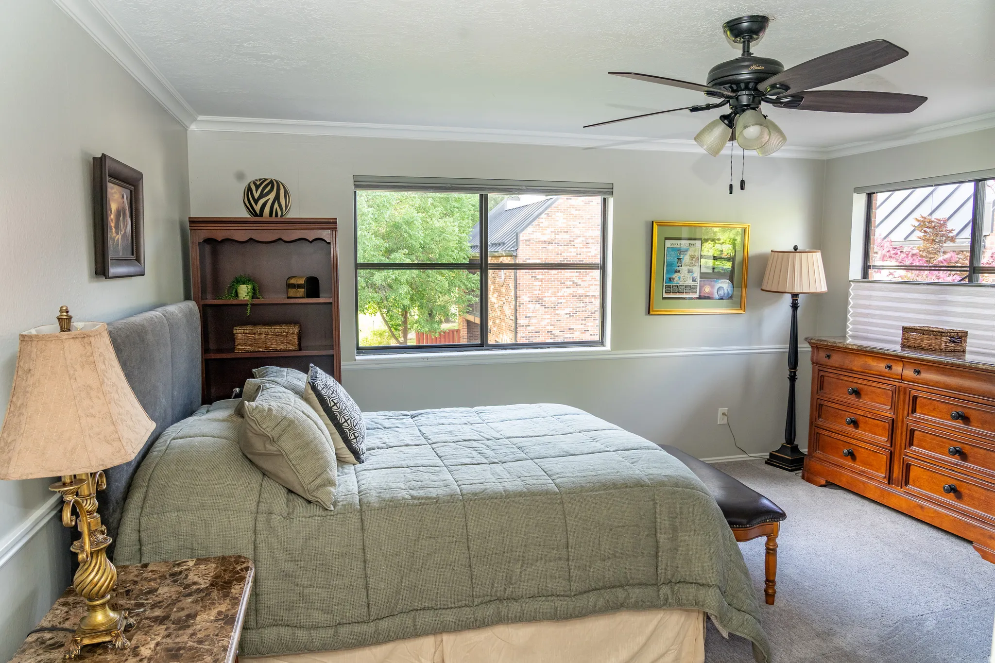 Carpeted room featuring a ceiling fan with integrated lighting, multiple windows with blinds, and white crown molding