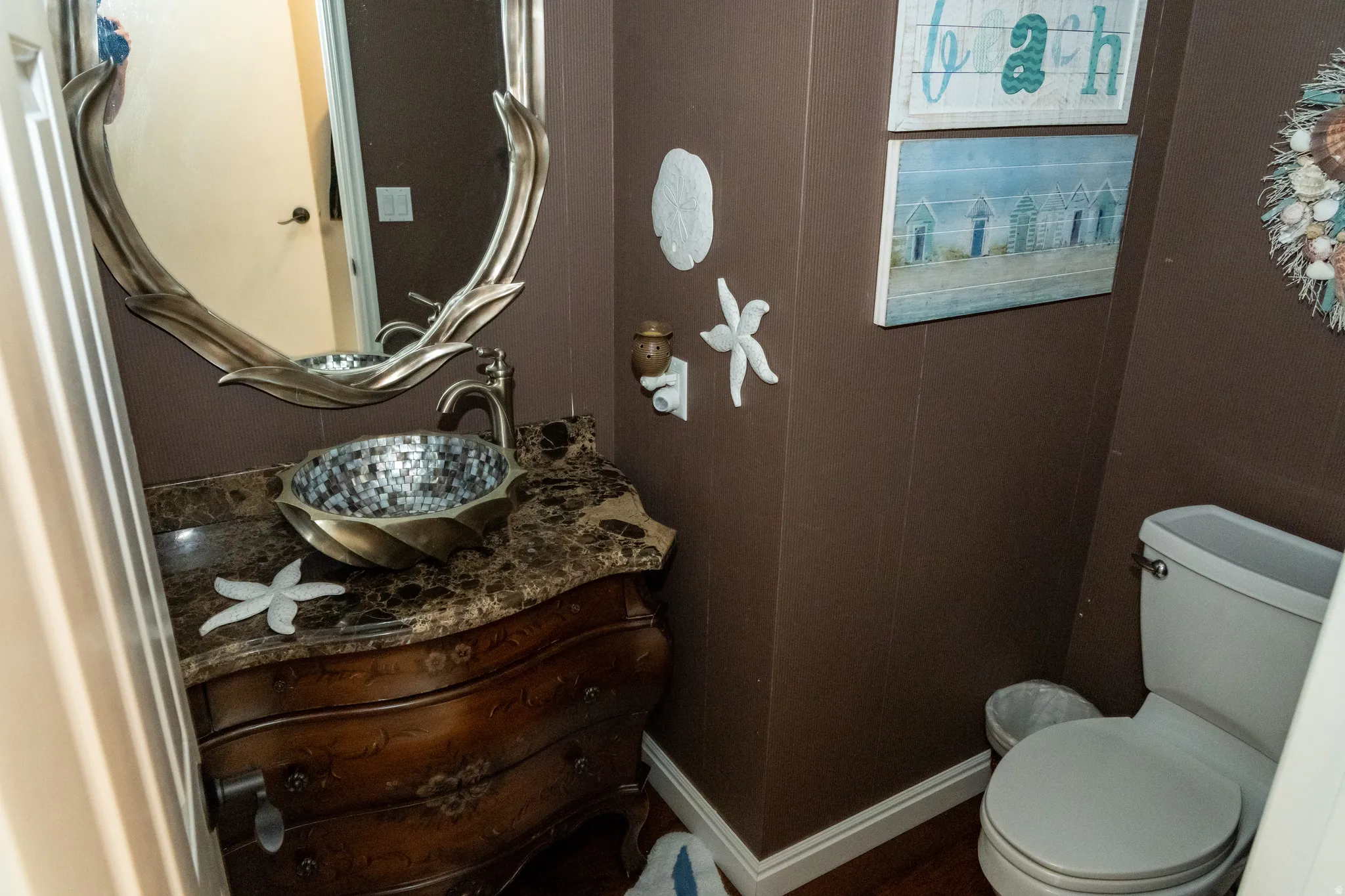 Vanity featuring a mosaic vessel sink, marble-finish countertop, and decorative mirror