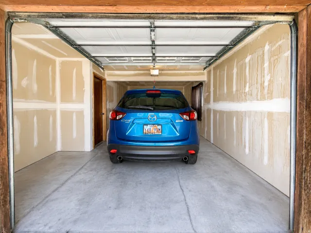 Single-car garage with concrete flooring, unfinished drywall, and an overhead garage door