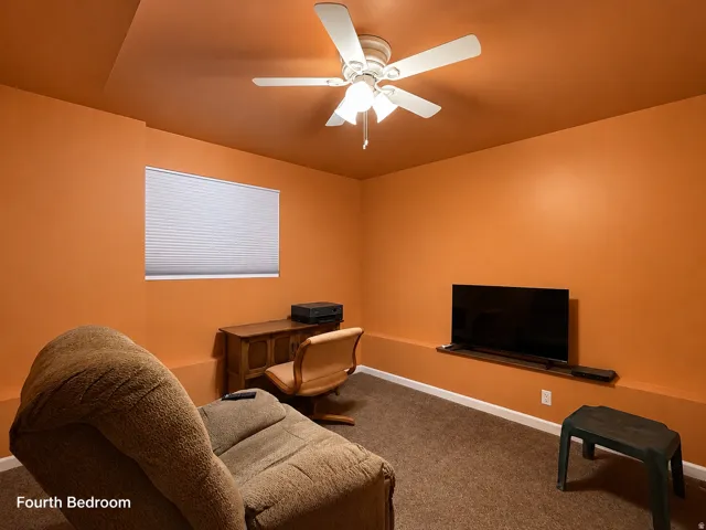 Room featuring textured carpet flooring, a window with horizontal blinds, and a ceiling fan with integrated lighting