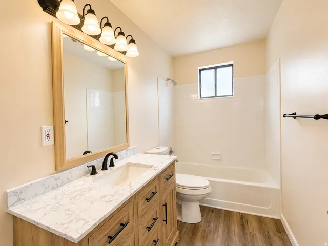 Bathroom featuring a light wood-finish vanity with a white countertop, an undermount sink, and a matte black two-handle faucet