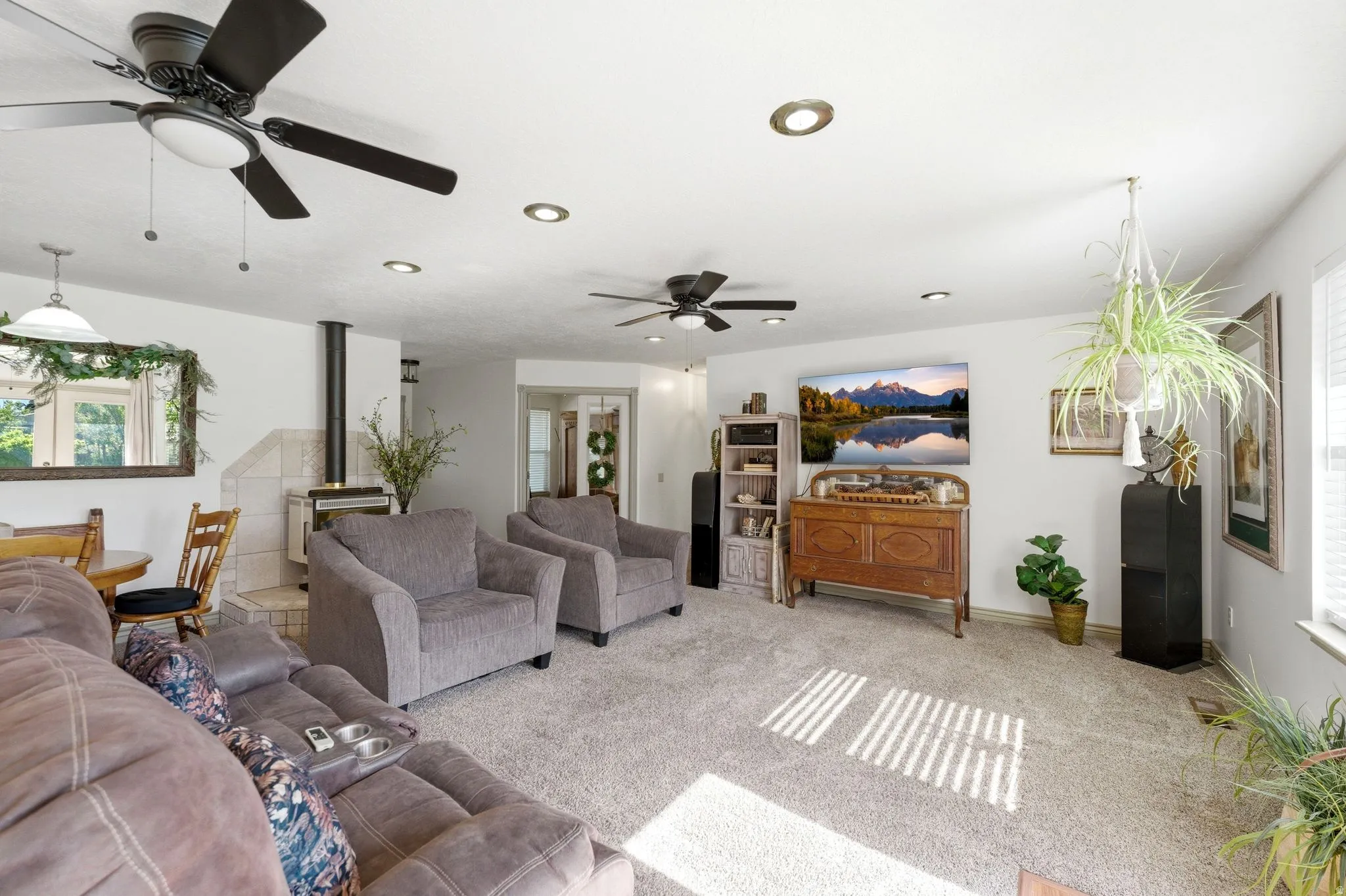 Spacious living area featuring neutral carpeting, recessed lighting, and multiple ceiling fans