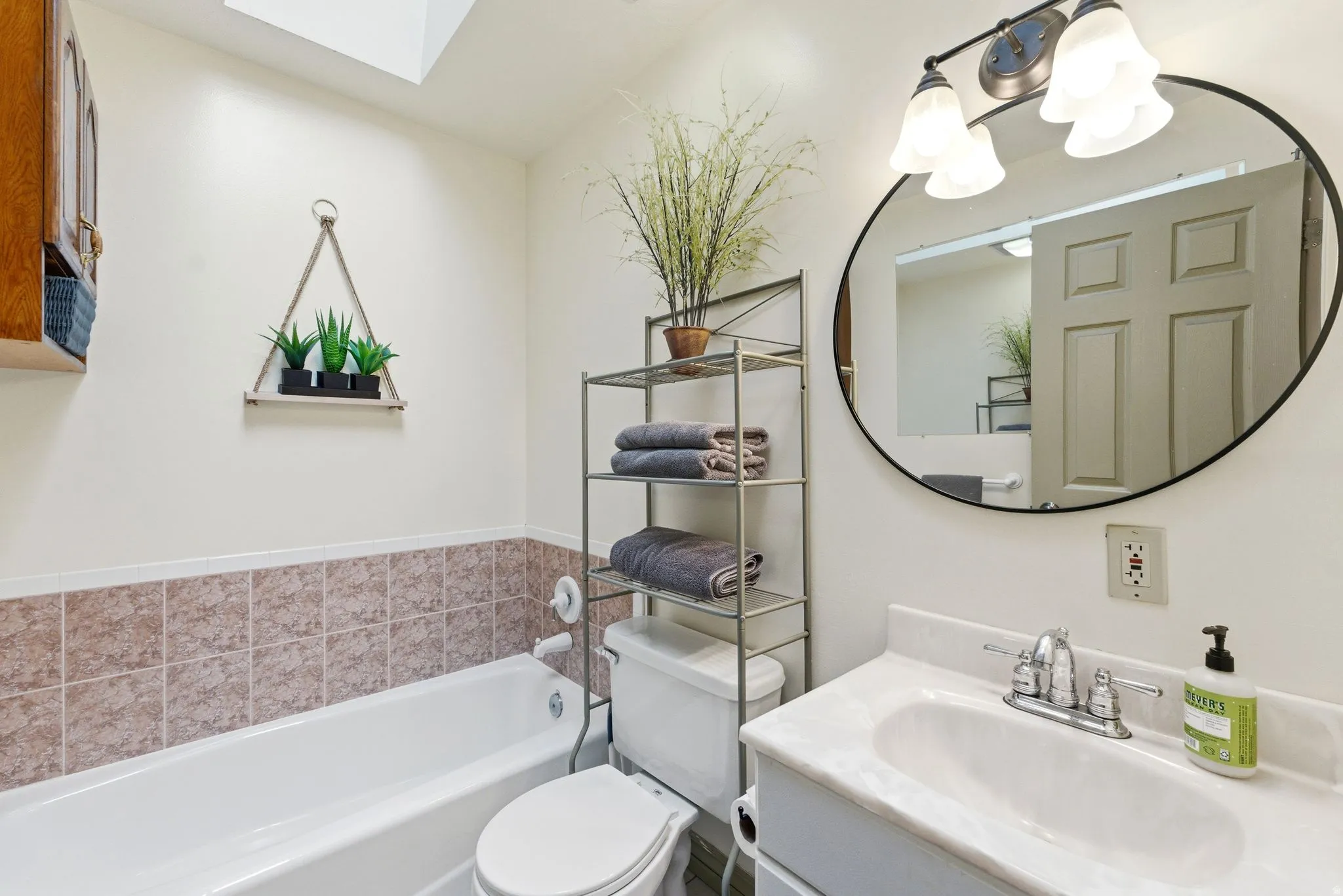 Bathroom featuring a white bathtub, tiled wall surround, and a skylight