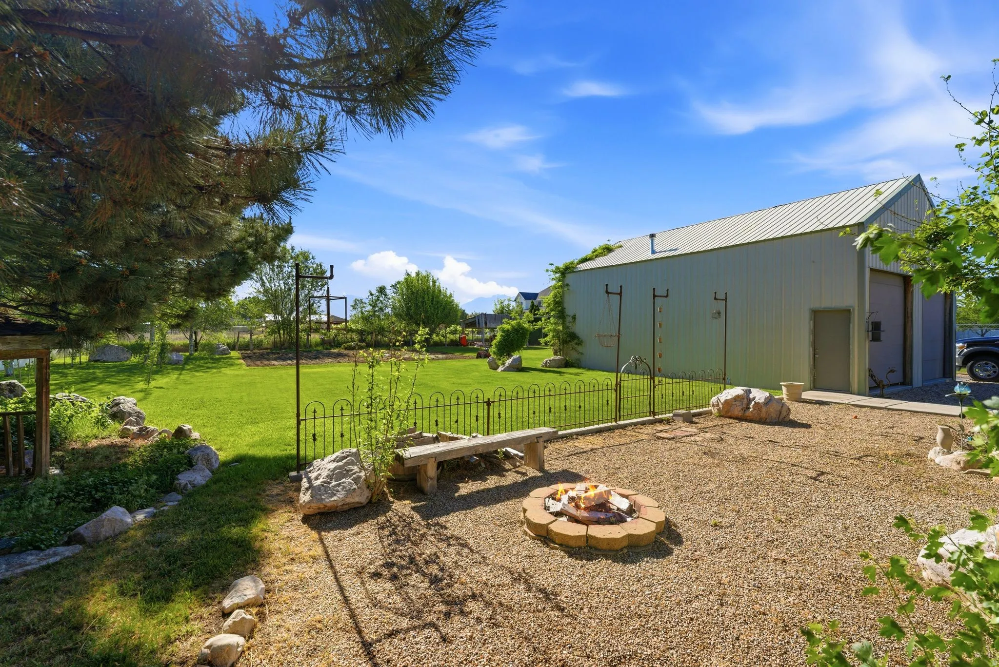 Expansive outdoor space featuring a stone-lined fire pit, a gravel patio area, and a stone bench