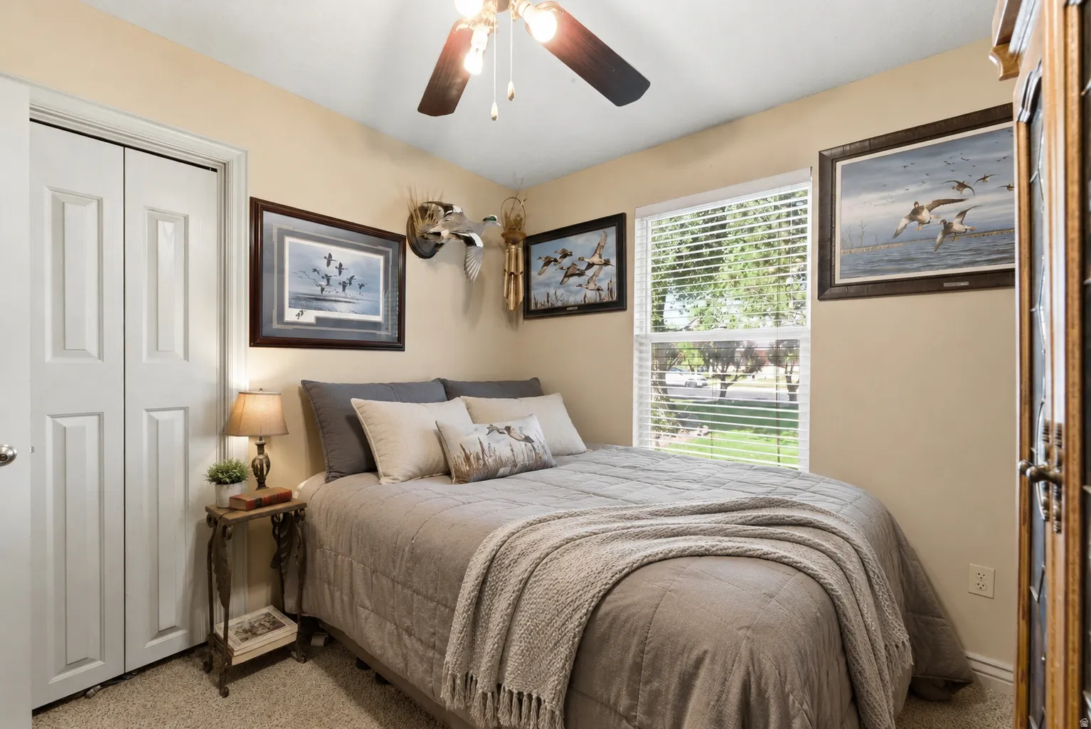 Bedroom featuring a double-pane window with blinds, bi-fold closet doors, wall-to-wall carpeting, a ceiling fan with integrated lighting, and neutral-toned walls