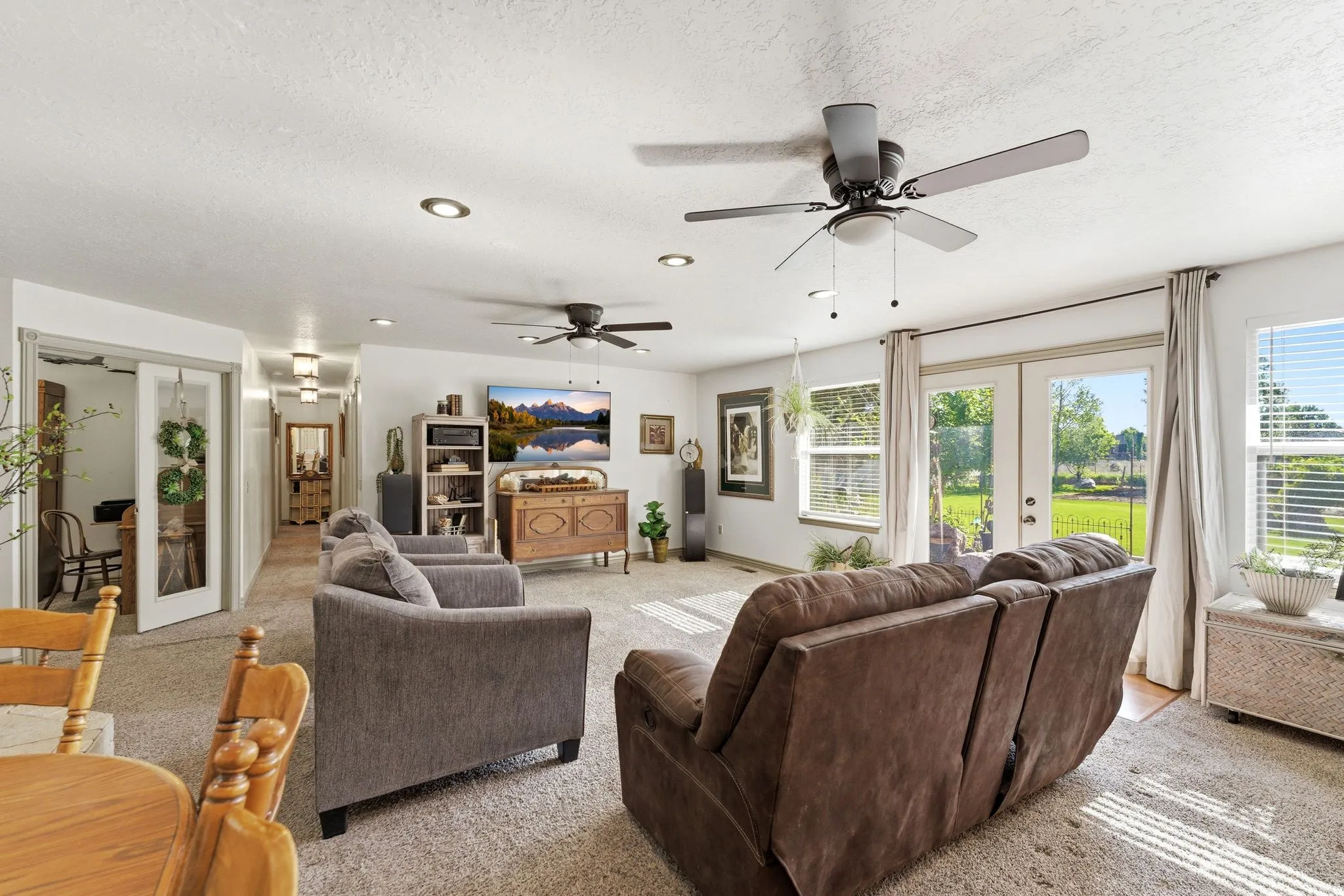 Spacious living area featuring carpet flooring, recessed lighting, and dual ceiling fans