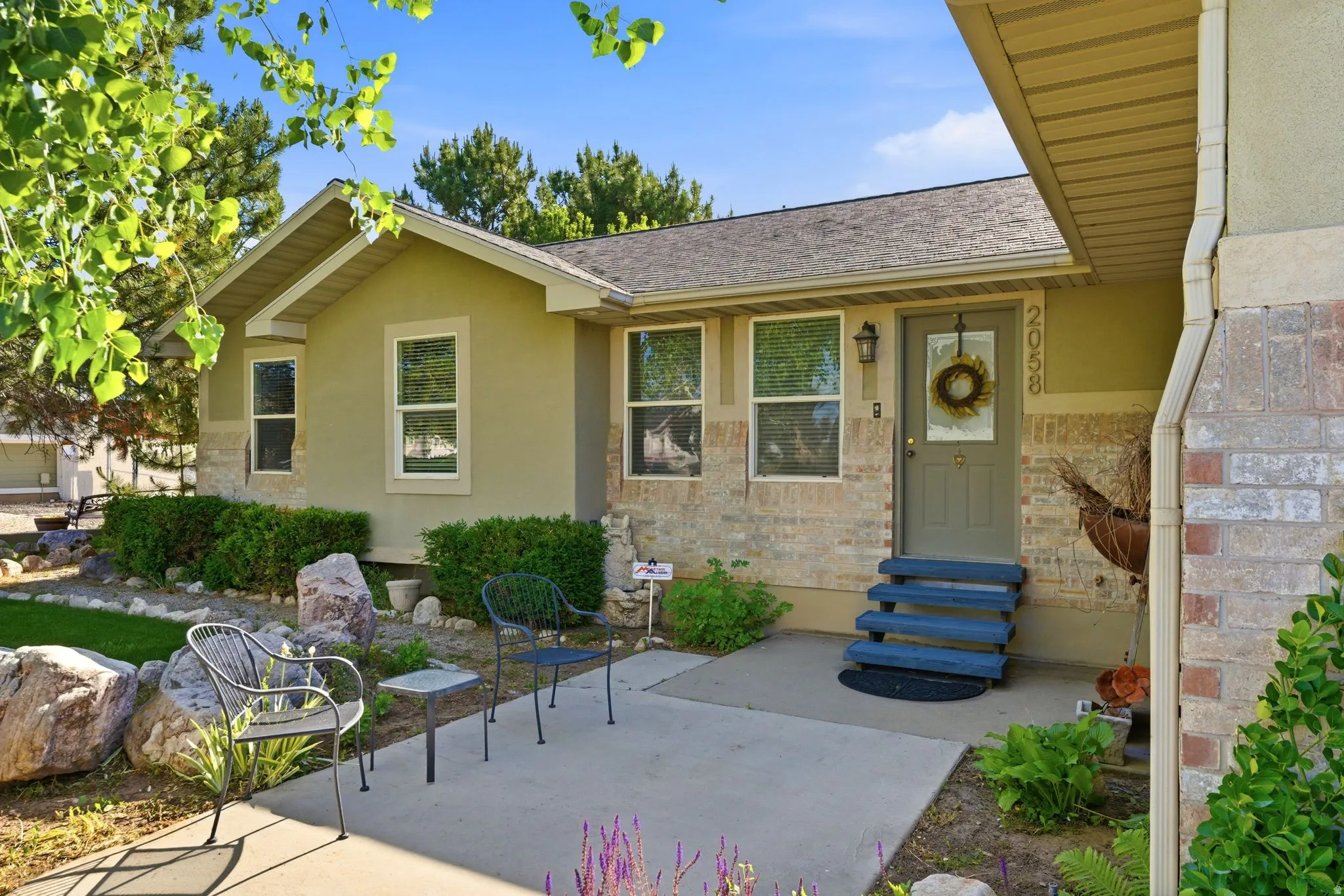 Stucco and brick exterior with a pitched shingle roof