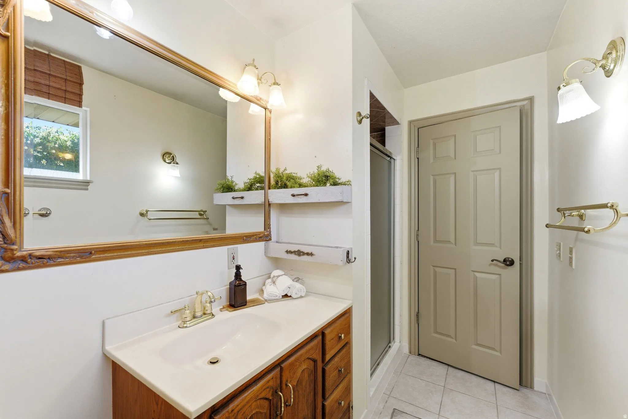 Bathroom featuring a vanity with a white countertop, wood-finish cabinetry, and a large framed mirror