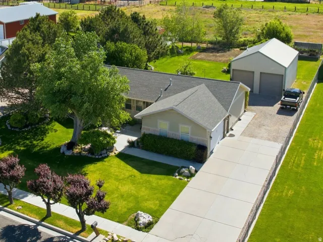 Expansive property featuring a detached two-car garage, mature landscaping, paved driveway, and established neighborhood setting with distant mountain scenery