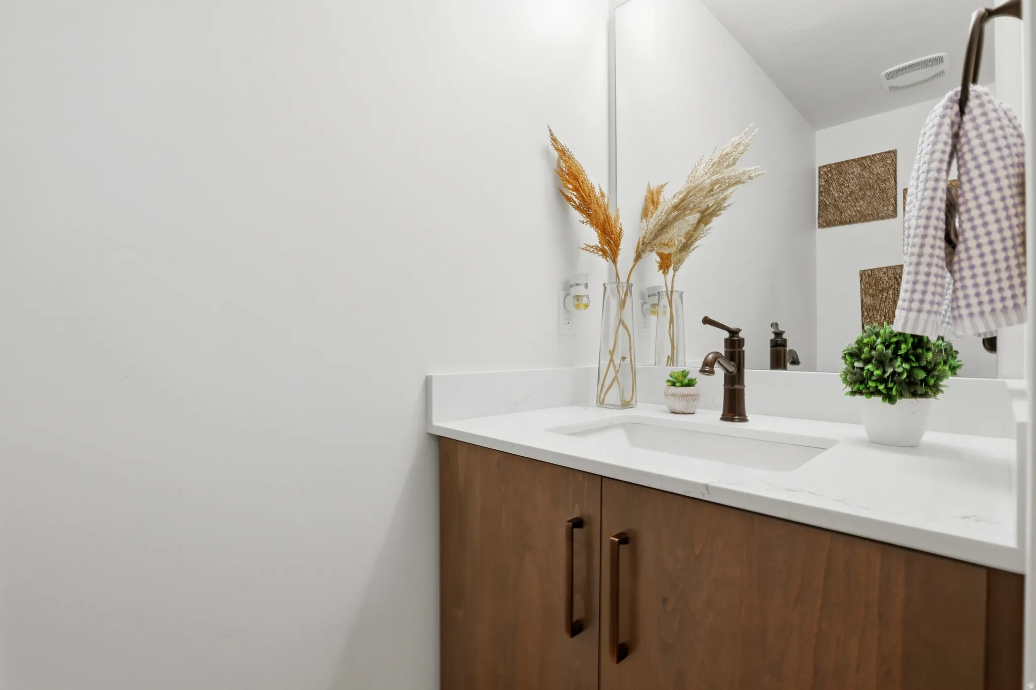 Modern vanity with a light wood-finish cabinet, integrated sink, and white countertop