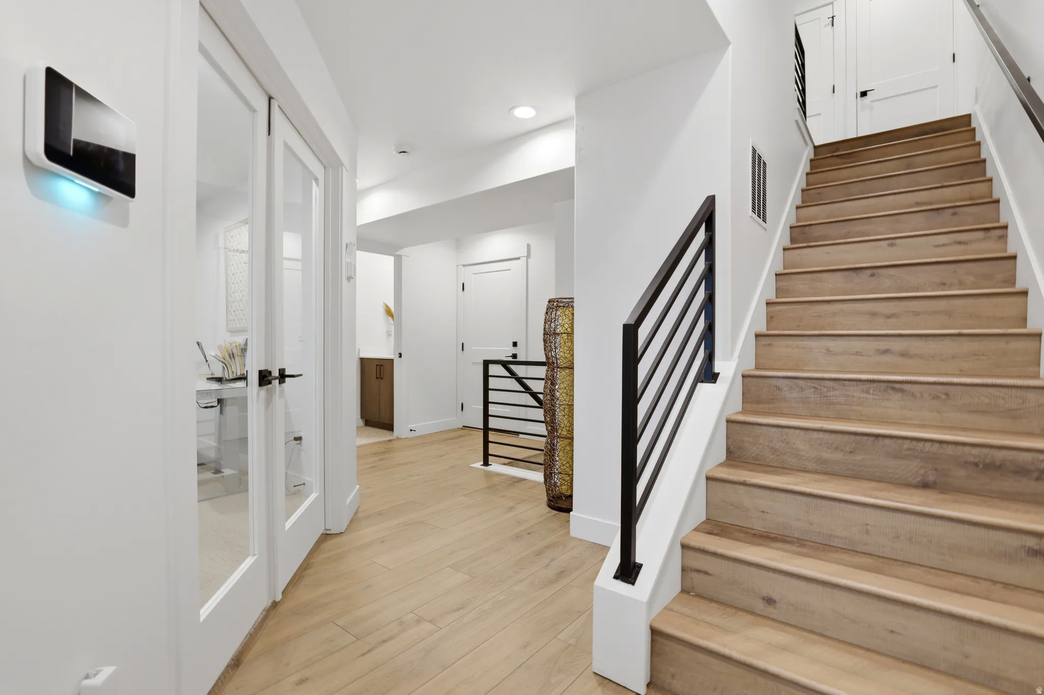 Staircase featuring wood-finish treads and risers, with a contemporary black metal baluster railing system