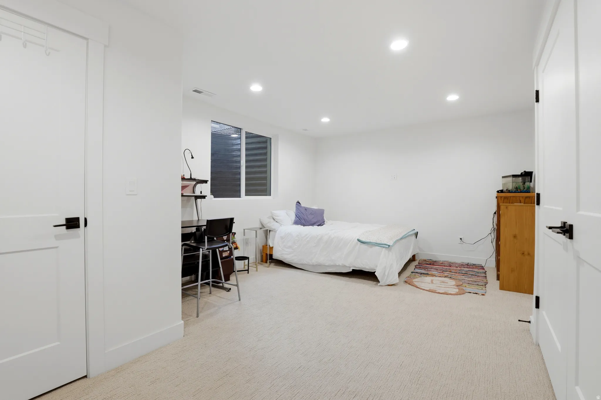 Recessed lighting illuminates this room featuring light-toned carpeting and neutral wall finishes