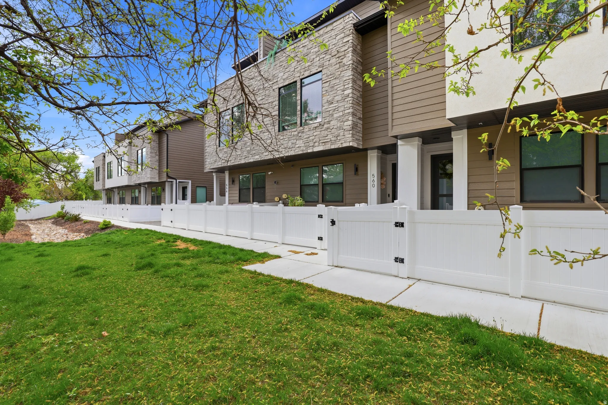 Contemporary townhome facade featuring stone veneer accents and horizontal siding