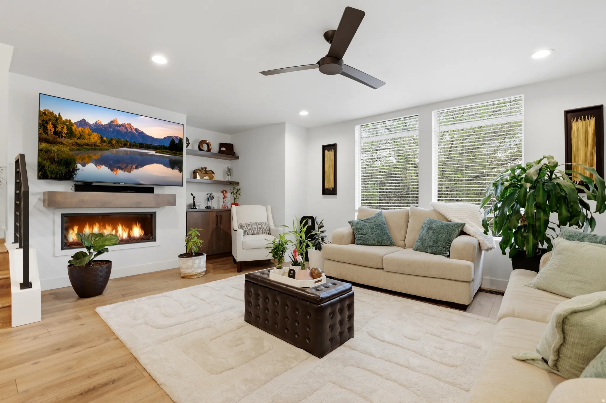 Open-concept living area featuring light wood-finish flooring, a contemporary linear fireplace with a floating mantel, and recessed ceiling lighting