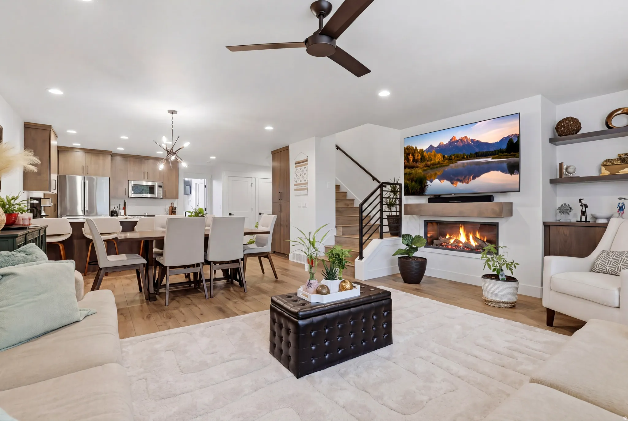 Open-concept living area featuring wood-finish flooring, a contemporary fireplace with a floating mantel, and built-in shelving