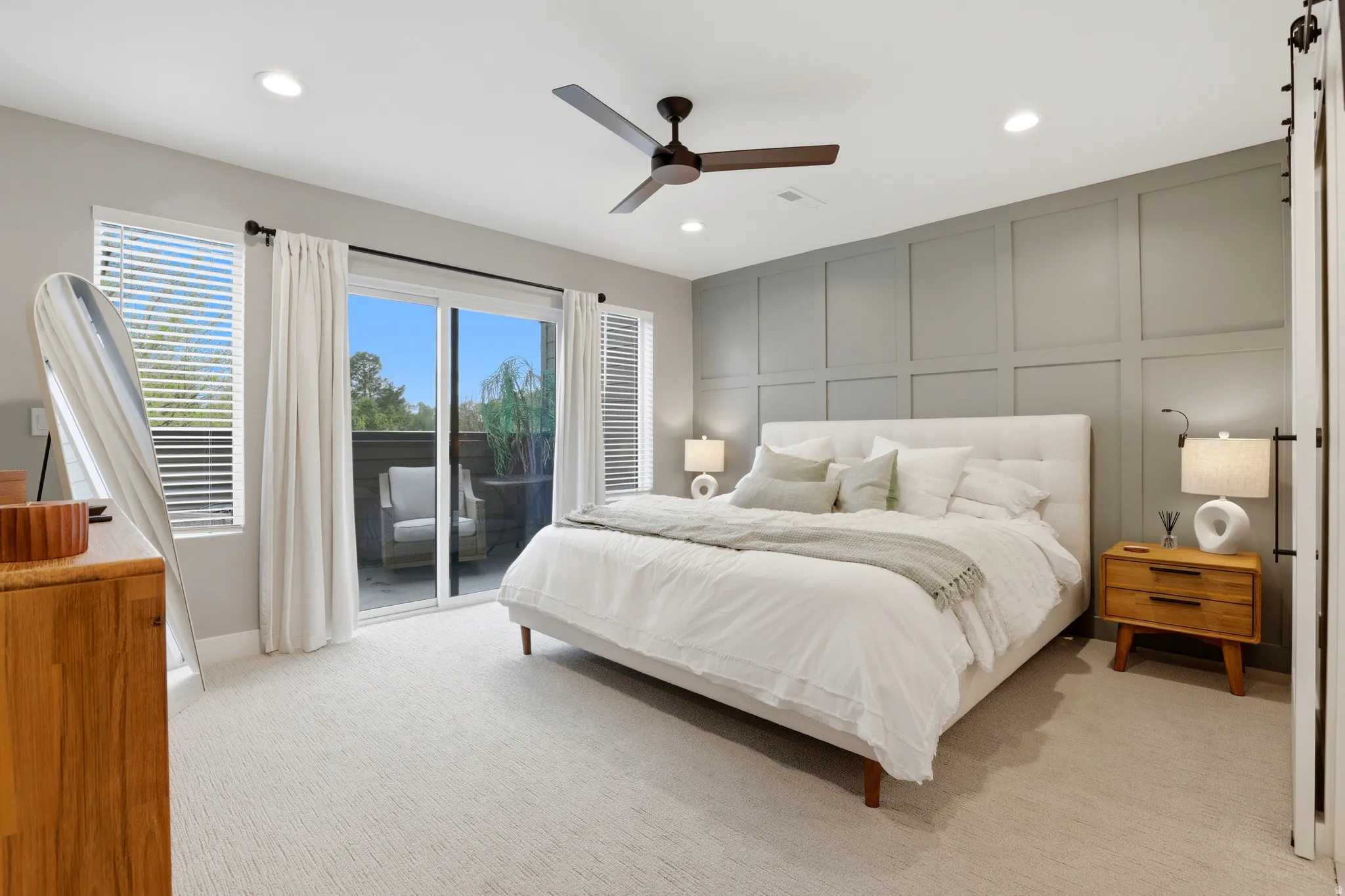 Spacious bedroom featuring light-colored carpeting and a contemporary ceiling fan
