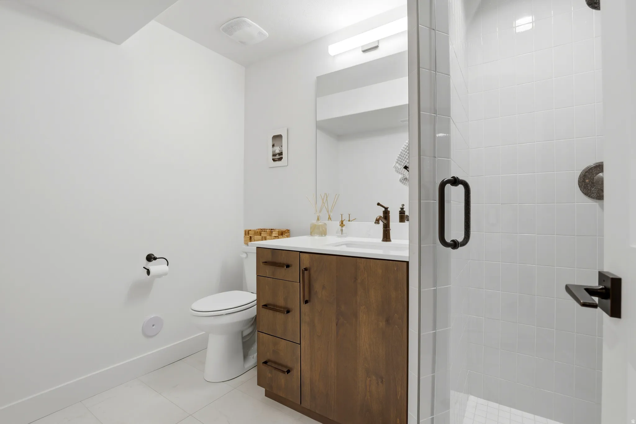 Modern bathroom featuring a wood-finish vanity with a white countertop and bronze-finish faucet