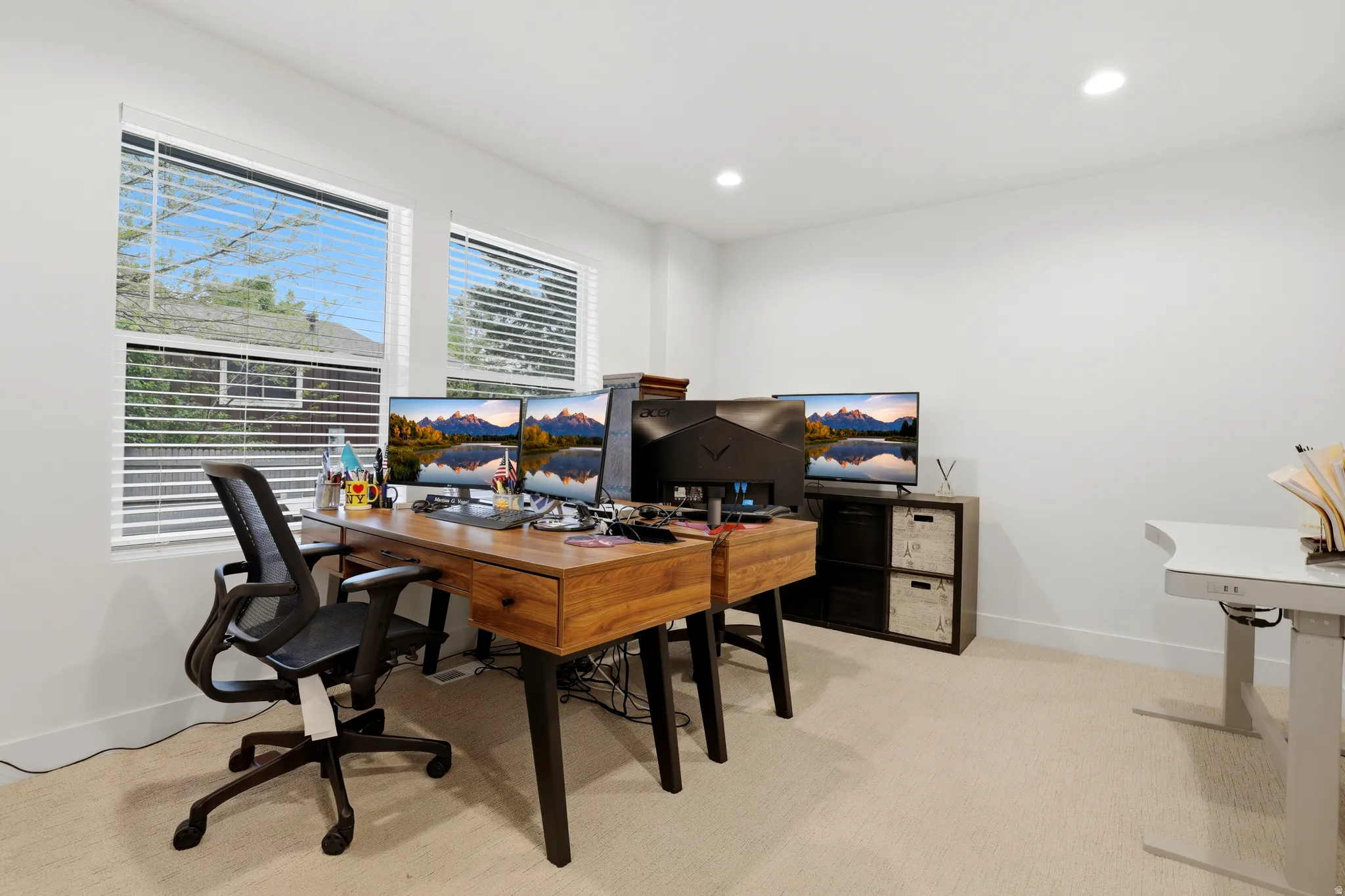 Bright room featuring two windows with horizontal blinds, neutral carpeting, recessed lighting, and white walls