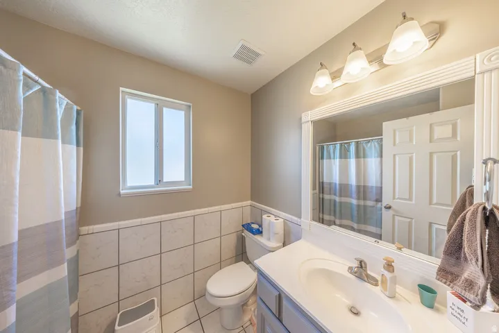 Full bathroom featuring a single vanity, a framed mirror, and a window
