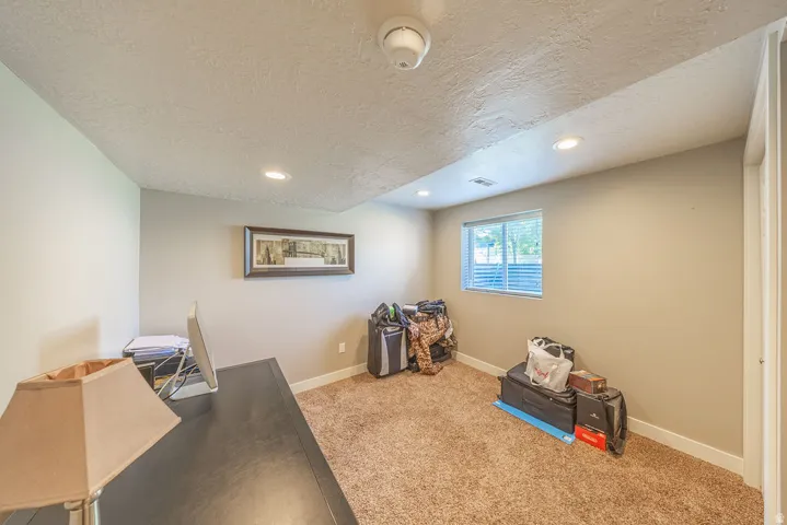 Carpeted room with recessed lighting and a window featuring horizontal blinds