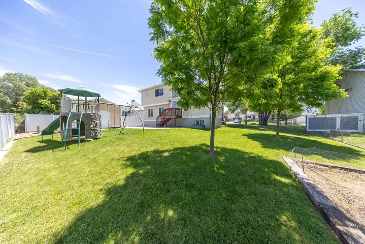 Spacious backyard featuring a manicured lawn, established shade trees, and a privacy fence