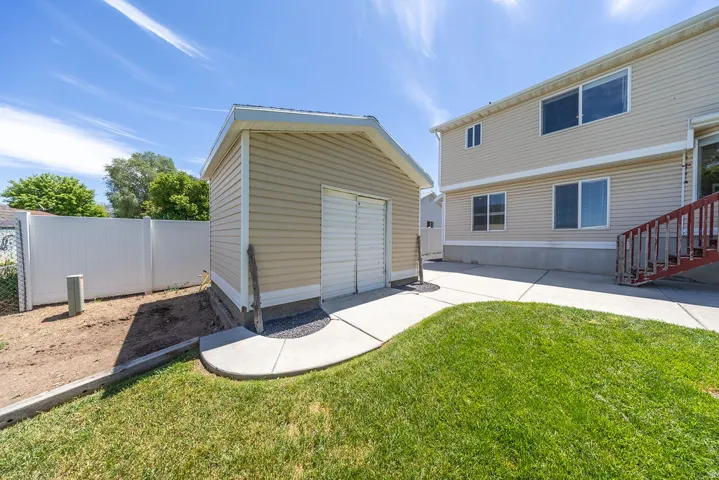 Detached utility shed featuring horizontal siding and a roll-up door